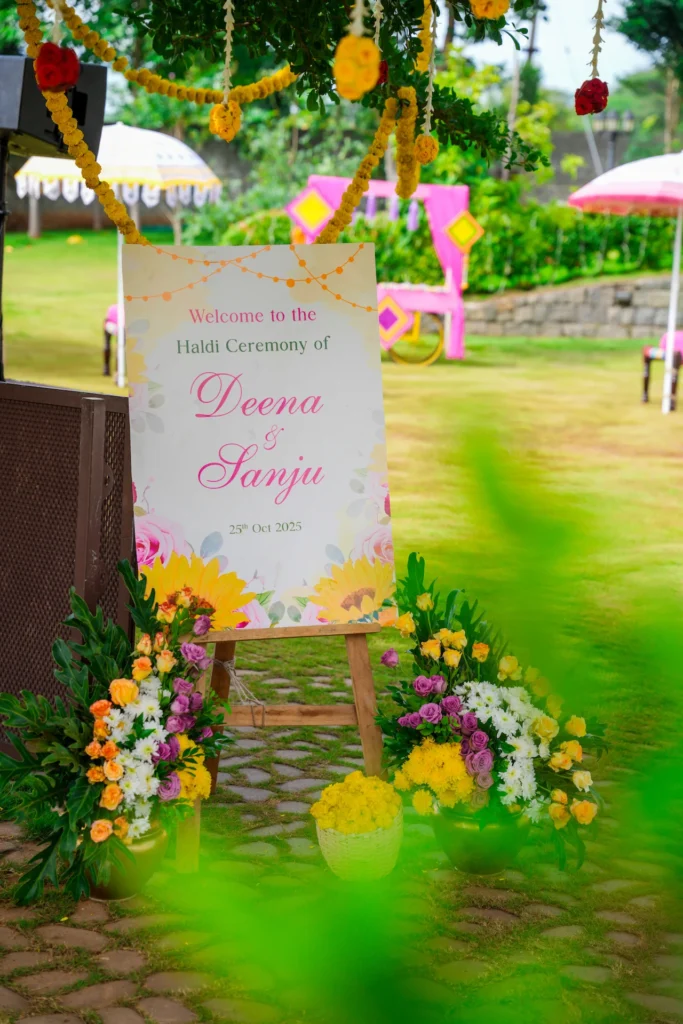 Haldi ceremony welcome sign for Deena and Sanju surrounded by colourful floral arrangements