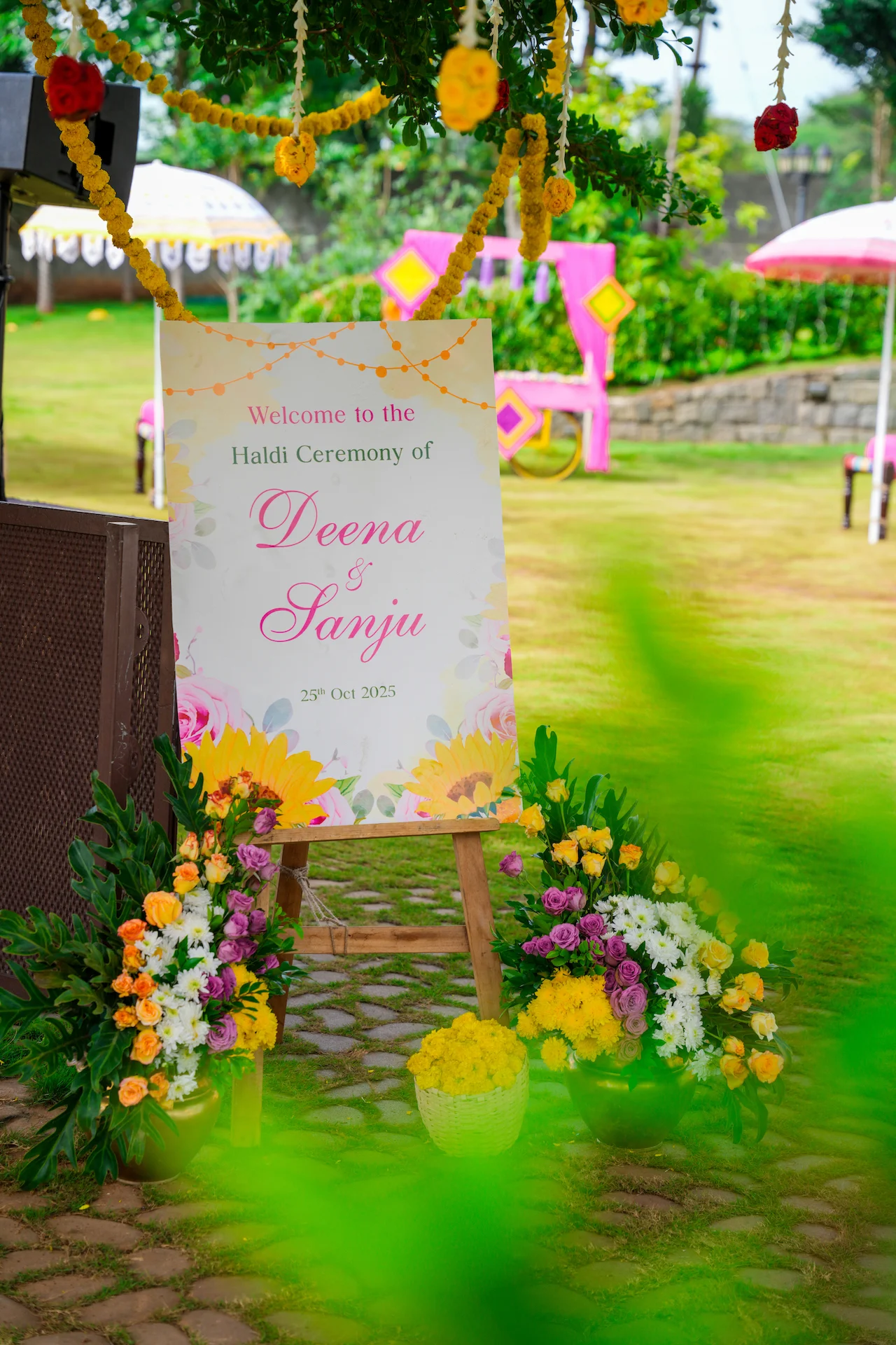 Haldi ceremony welcome sign for Deena and Sanju surrounded by colourful floral arrangements